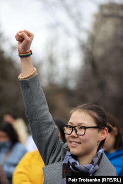 Әйел құқығын қорғауға арналған митингіге қатысушылардың бірі жұдырығын түйіп, оң қолын көтеріп, тұр. Алматы, 8 наурыз 2022 жыл.