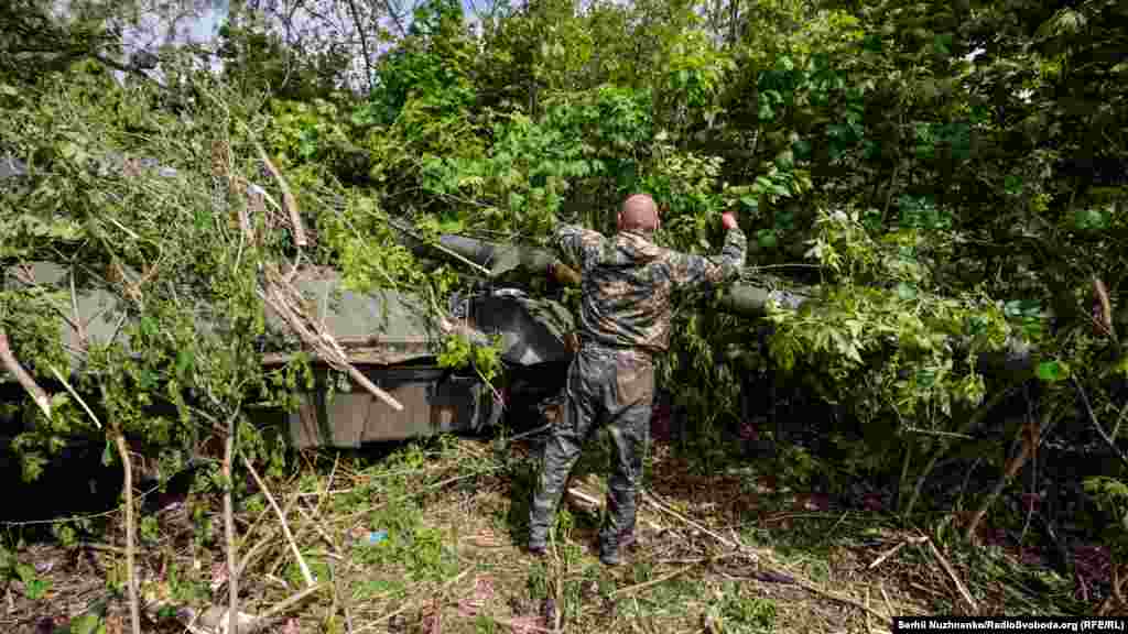 Український військовий маскує на позиціях захоплений у бою&nbsp;російський&nbsp;танк Т-80. Харківська область, 1 травня 2022 року&nbsp;