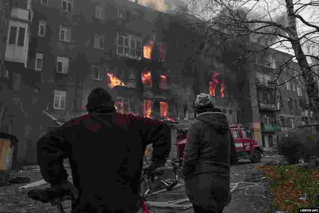 Люди дивляться, як горить їхній будинок після російського обстрілу 7 грудня. До повномасштабного вторгнення Росії в Україну населення міста становило 70 000 людей. Бахмут відомий переважно своїми великими соляними шахтами та виноградниками