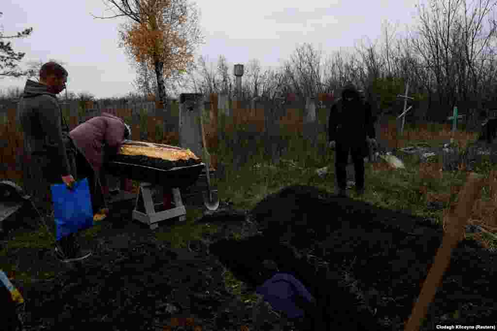 Мати плаче над труною сина. Сіре небо накриває пошкоджене вирвами від снарядів кладовище