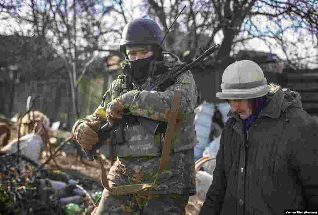 Український військовий супроводжує місцеву жительку, Бахмут, 7 грудня 2022 року. Не лише обстріли, а й зимові місяці без світла та води є серйозними випробуваннями для жителів Бахмута