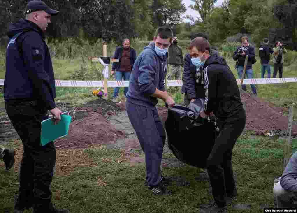 Український поліцейський 13 вересня спостерігає за ексгумацією тіла людини, яку, за даними правоохоронців, вбили російські війська в Балаклії &nbsp;