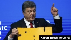 Президент Петро Порошенко демонструє на міжнародному форумі в Давосі уламок цивільного автобуса, знищеного російською ракетою у Волновасі (21 січня 2015 року)