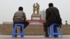 China - TO GO WITH CHINA-XINJIANG-UNREST-MIGRATION-POPULATION BY BENJAMIN HAAS This photo taken on April 16, 2015 shows a Uighur man and boy watching a performance under a statue of late communist leader Mao Zedong meeting with a Uighur, in the central 