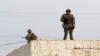 Kazakhstan - In this photo taken Saturday, Dec. 17, 2011, armed Kazakh soldiers stand on a top of a building in center of Zhanaozen, Kazakhstan. Kazakhstan President Nursultan Nazarbayev on Saturday imposed a three-week state of emergency in an oil town w