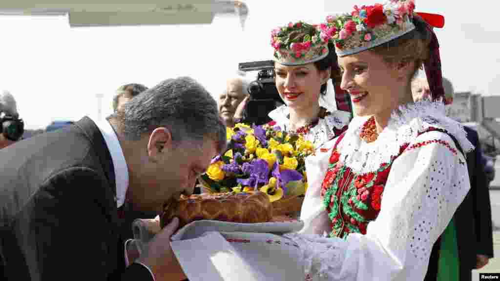 Украина президенті Петр Порошенко өзін әуежайда қарсы алғанда ежелгі дәстүр бойынша ұсынылған нан-тұздан дәм татып тұр.&nbsp;Минск, 26 тамыз 2014 жыл.